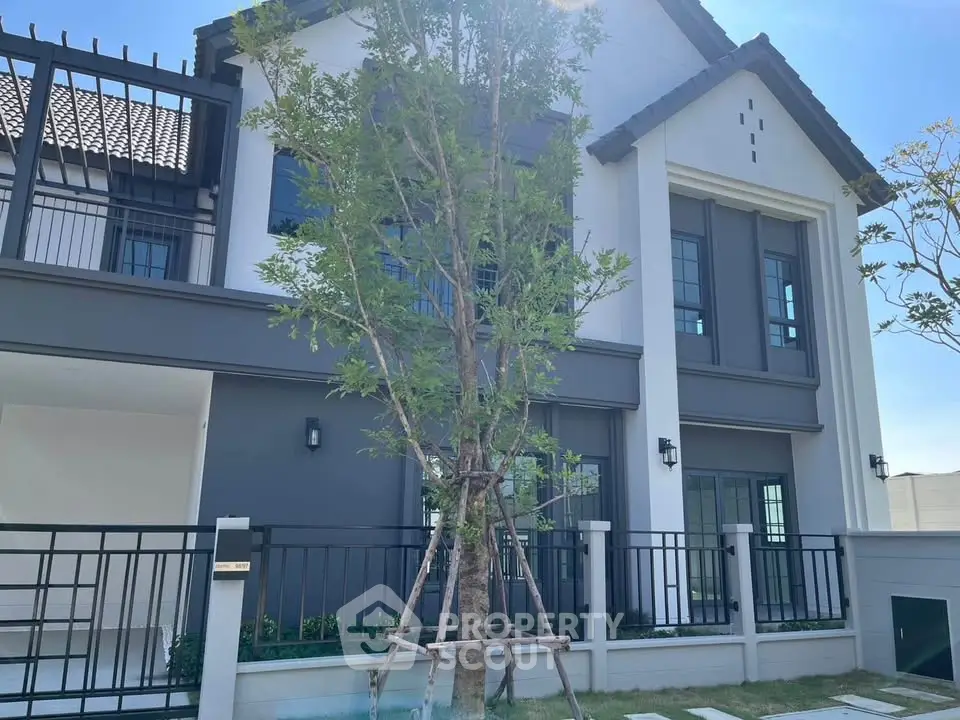 Modern two-story house with sleek design and large windows, featuring a landscaped front yard and contemporary architecture.