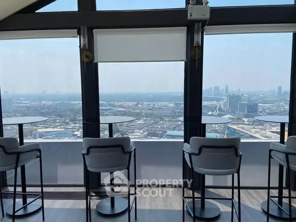 Stunning high-rise view from modern rooftop lounge with sleek seating and panoramic cityscape.