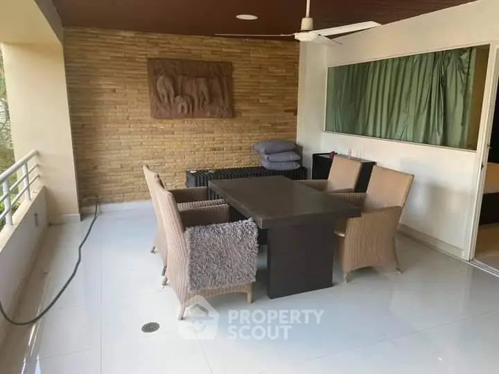 Spacious balcony with modern wicker furniture set against a brick feature wall, perfect for outdoor relaxation and entertaining guests.