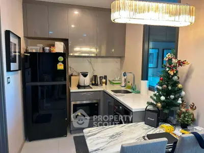 Modern kitchen with sleek appliances and festive decor, featuring a marble countertop and elegant lighting.