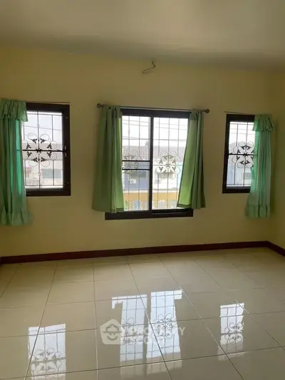 Spacious room with large windows and tiled flooring, perfect for natural light and comfort.