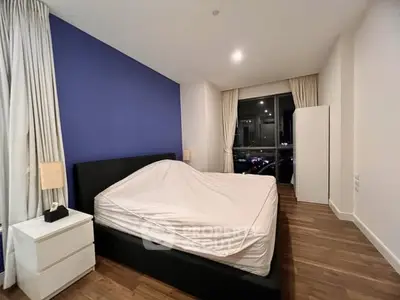 Modern bedroom with large window and stylish decor in urban apartment.