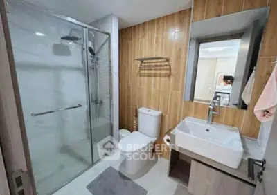 Modern bathroom with glass shower and wooden accents in a stylish apartment.