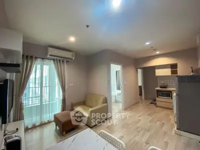Modern open-plan living room with kitchen in a stylish apartment, featuring natural light and contemporary furnishings.