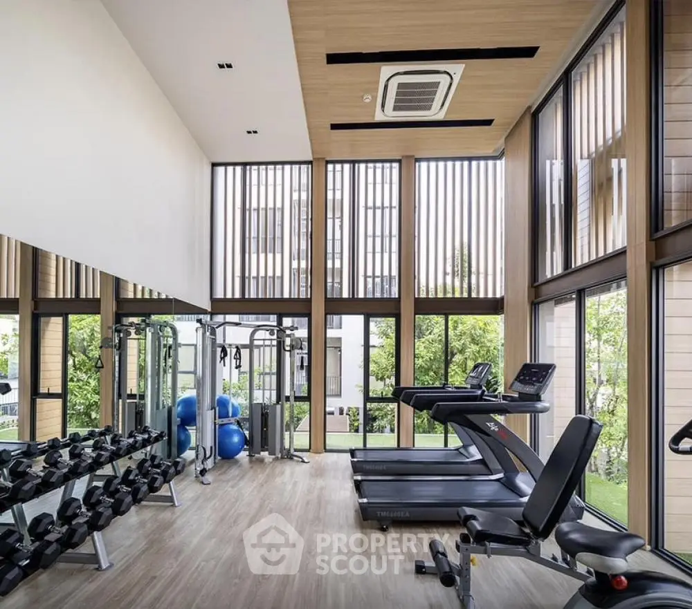 Modern gym with large windows and fitness equipment in luxury residential building.