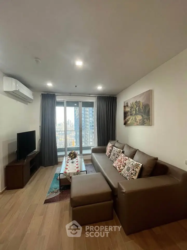 Modern living room with large sofa, TV, and balcony view in stylish apartment.