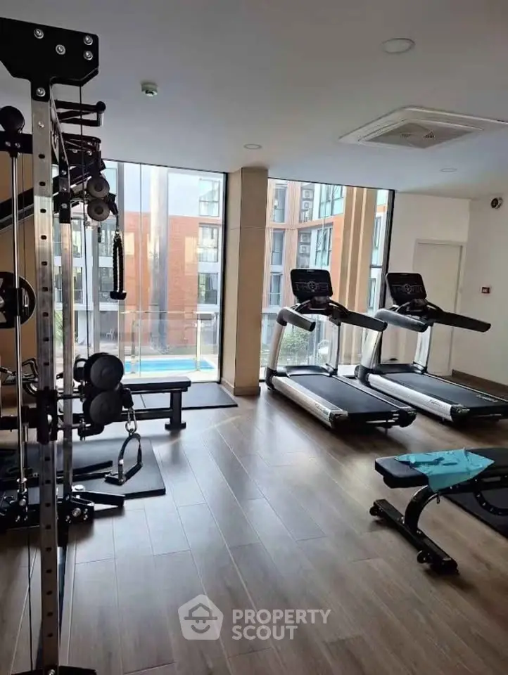 Modern gym with state-of-the-art equipment and large windows offering a bright and inviting workout space.