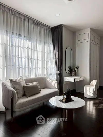 Elegant living room with modern sofa, stylish coffee table, and natural light through sheer curtains.