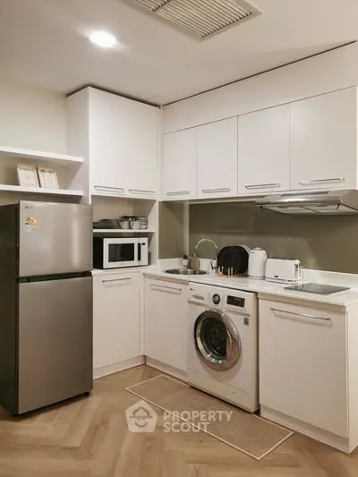 Modern kitchen with sleek appliances and washing machine in a compact layout.