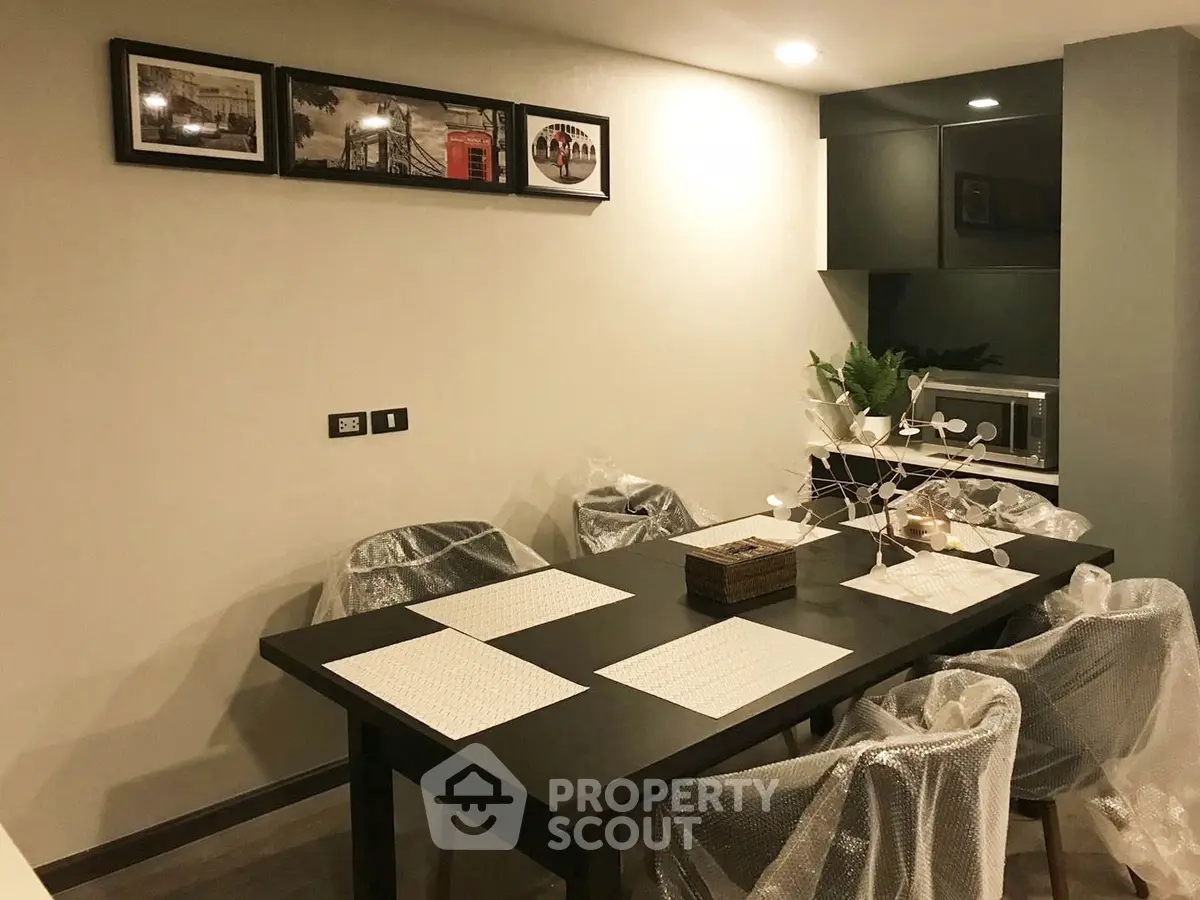 Modern dining area with sleek black table and chairs, featuring contemporary decor and ambient lighting.