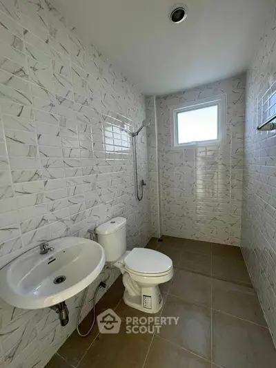 Modern minimalist bathroom with tiled walls and natural light.