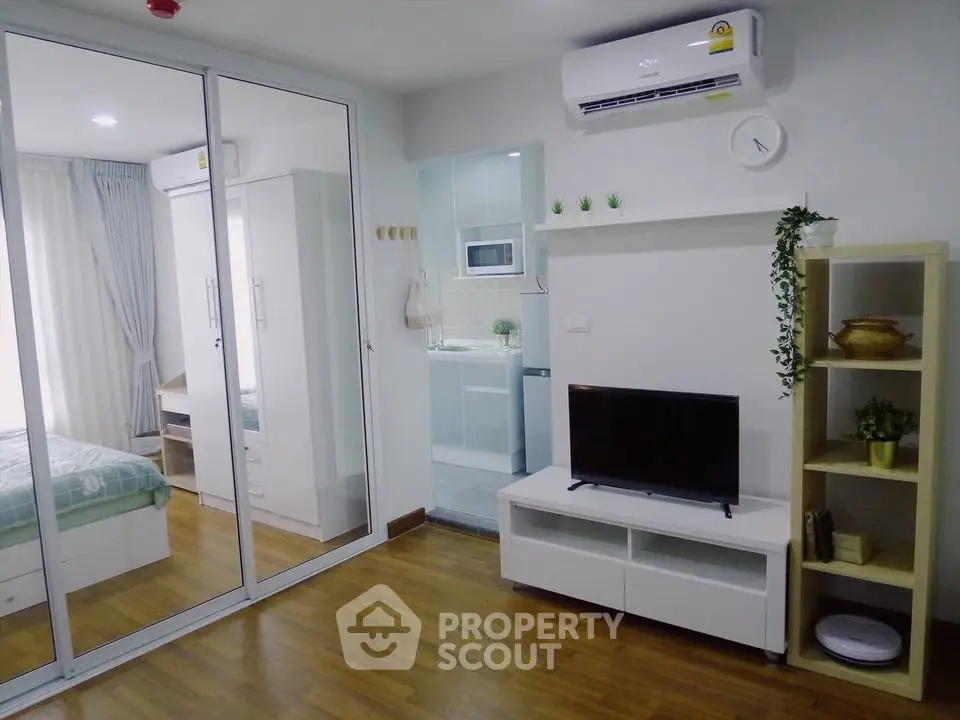 Modern living room with wooden flooring, TV unit, and air conditioning in a cozy apartment.