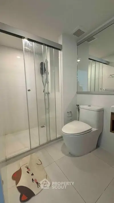 Modern bathroom with glass shower and sleek fixtures in contemporary apartment.