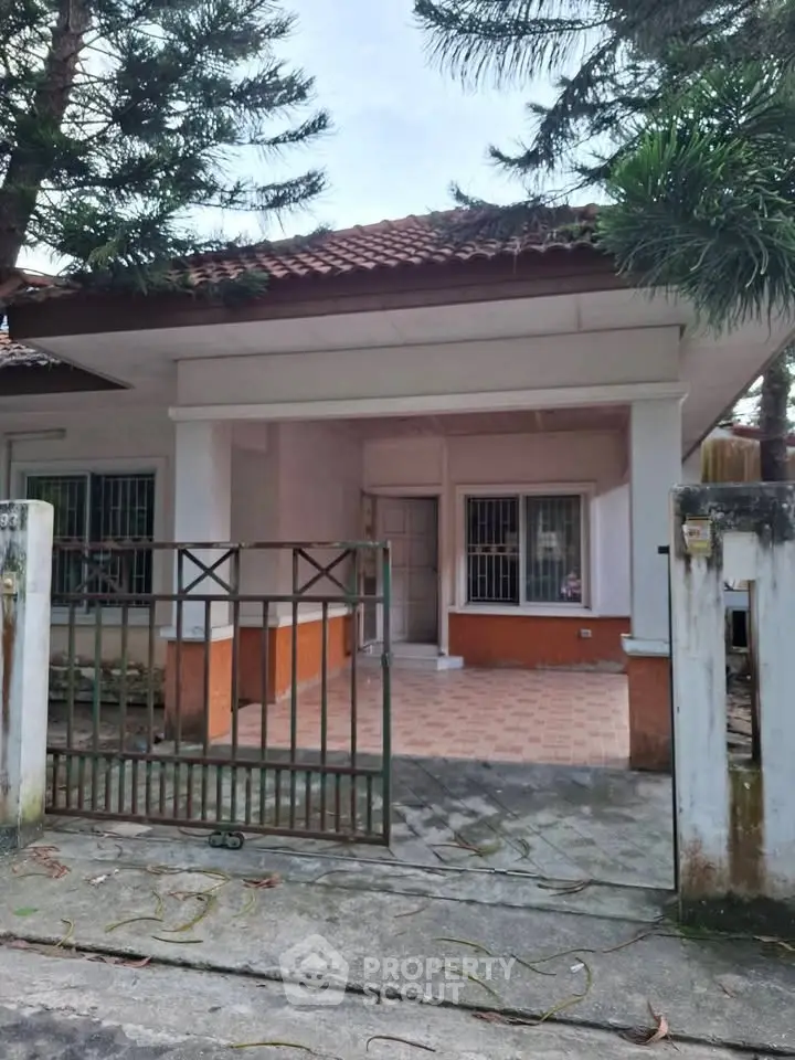 Charming single-story house with gated entrance and tiled porch in a serene neighborhood.