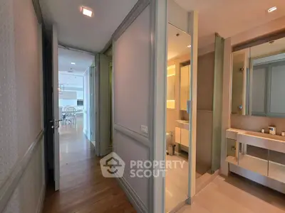 Modern apartment hallway leading to a stylish bathroom with elegant fixtures.