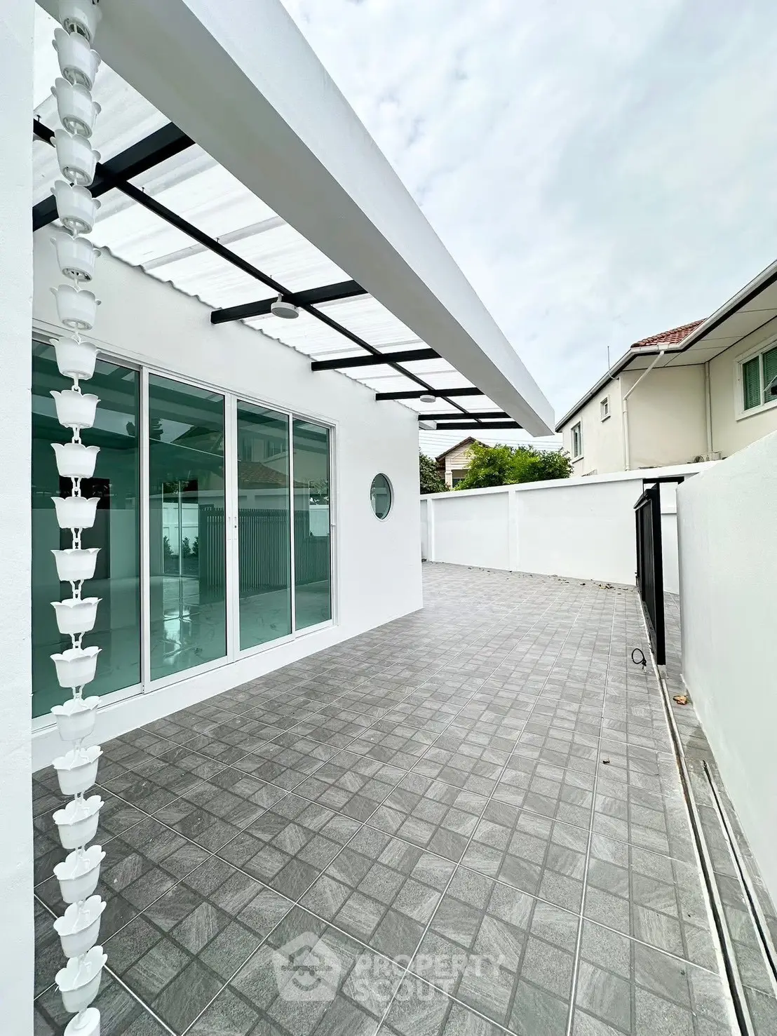 Spacious modern patio with sleek tile flooring and glass doors, perfect for outdoor relaxation.