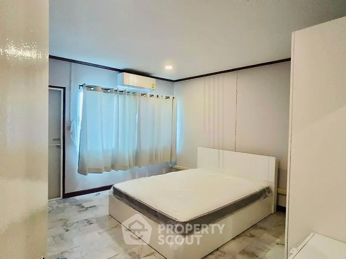 Spacious bedroom with modern decor and natural light, featuring a comfortable bed and stylish flooring.