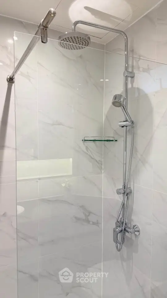 Modern bathroom shower with sleek chrome fixtures and elegant marble tiles.