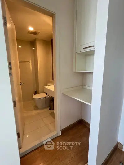 Compact bathroom with modern fixtures and adjacent built-in storage in a cozy apartment.