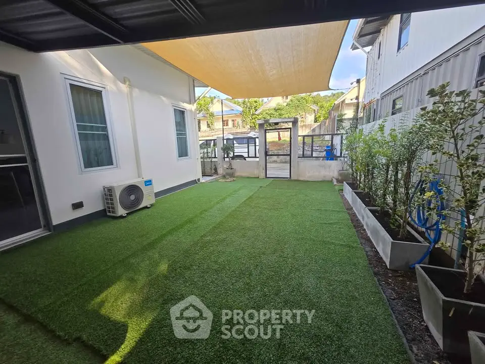 Charming backyard with artificial grass and shade sail, perfect for outdoor relaxation and entertainment.