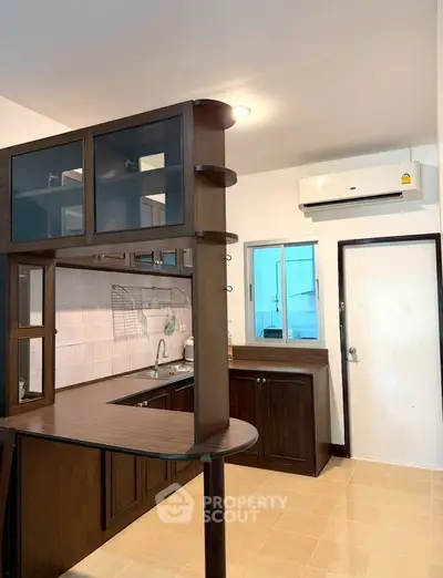 Modern kitchen with dark wood cabinets and open layout, featuring air conditioning and sleek design.