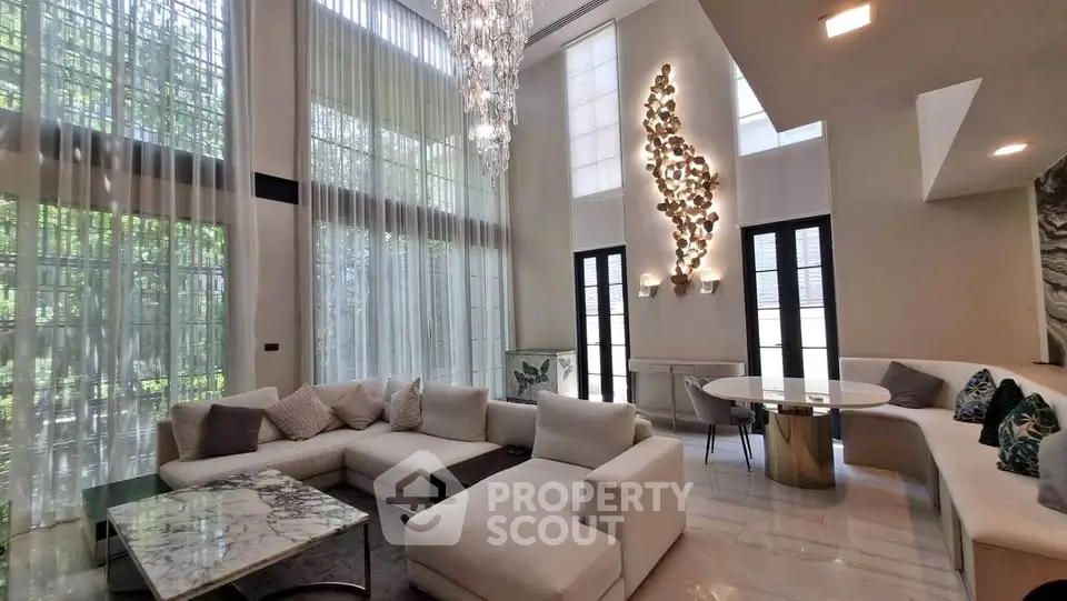 Luxurious modern living room with high ceilings, elegant chandelier, and stylish furniture.