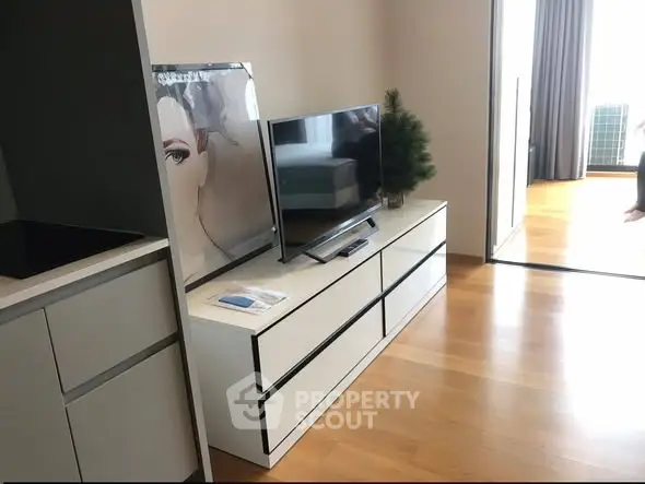Modern living room with sleek TV stand and hardwood floors in a stylish apartment.