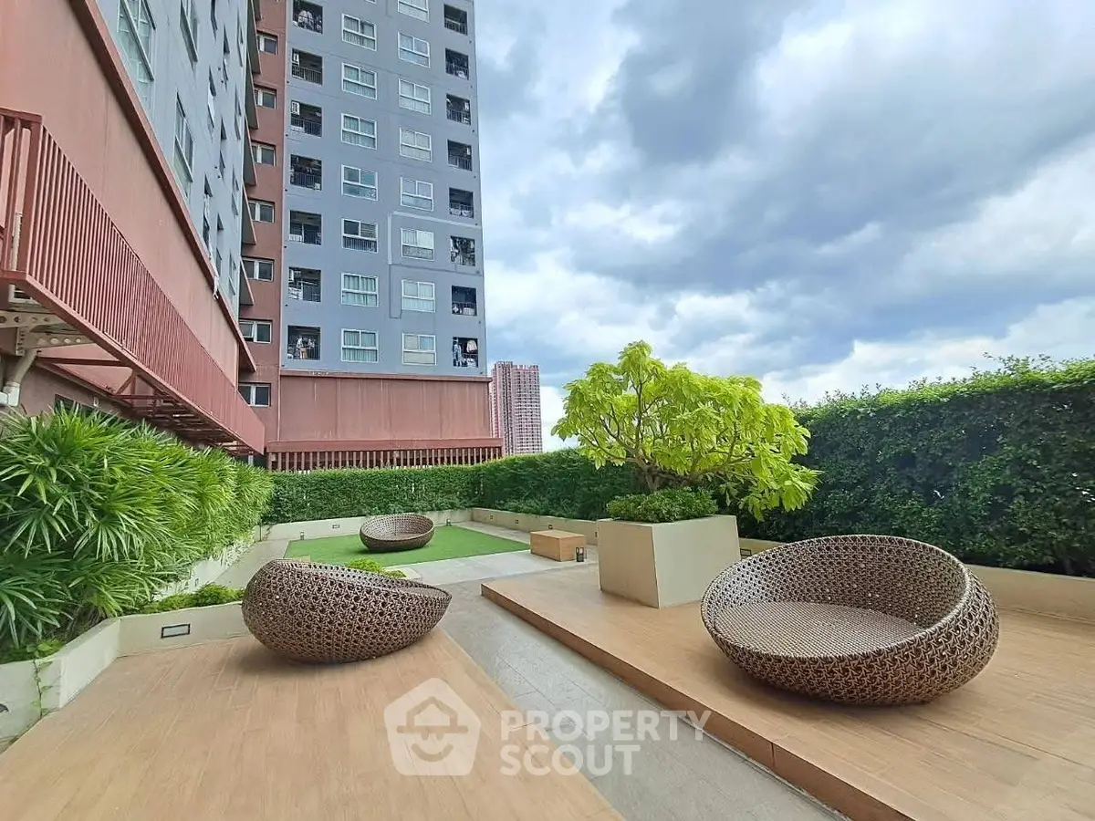 Modern apartment building with stylish outdoor seating area and lush greenery.