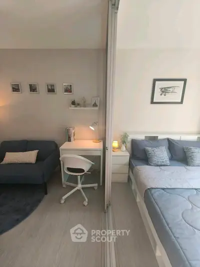 Modern studio apartment with cozy living area and stylish bedroom separated by sliding glass doors.