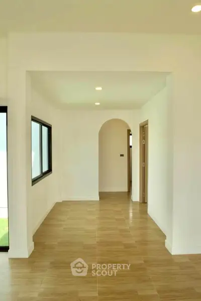 Spacious hallway with wooden flooring and modern lighting in a contemporary home.