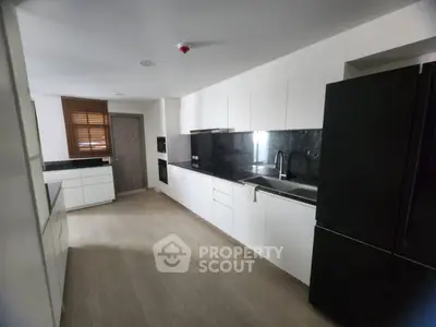 Modern kitchen with sleek black and white design, featuring ample storage and contemporary appliances.