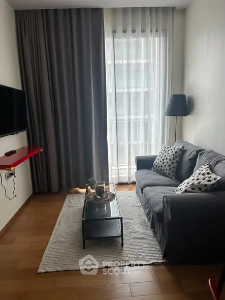 Cozy living room with modern decor, featuring a comfortable sofa, stylish coffee table, and large window with curtains.