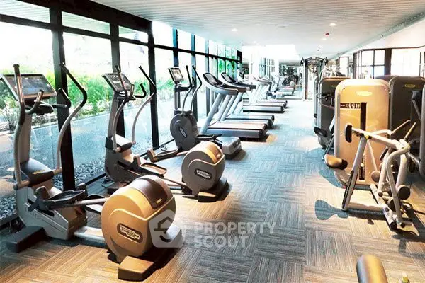 Modern gym with state-of-the-art fitness equipment and large windows for natural light.