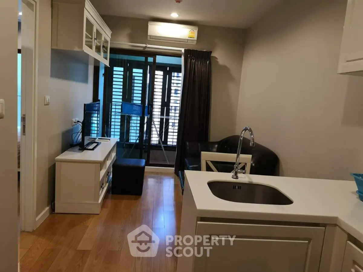 Modern living room with open kitchen and balcony view in a stylish apartment.