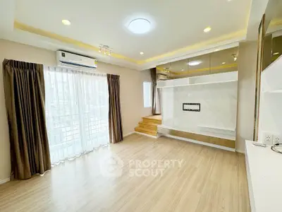 Spacious modern living room with wooden flooring and large window for natural light.
