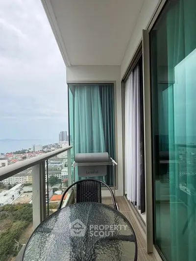 Stunning high-rise balcony with glass table and city view, perfect for relaxation and entertaining.