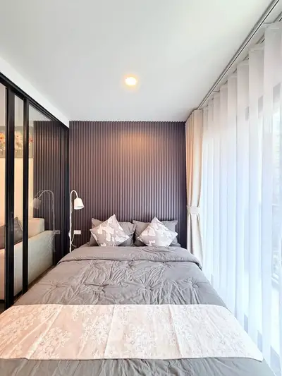 Modern bedroom with stylish decor and floor-to-ceiling windows in a contemporary apartment.