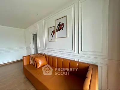 Elegant living room with stylish leather sofa and equestrian artwork, featuring classic wall paneling.