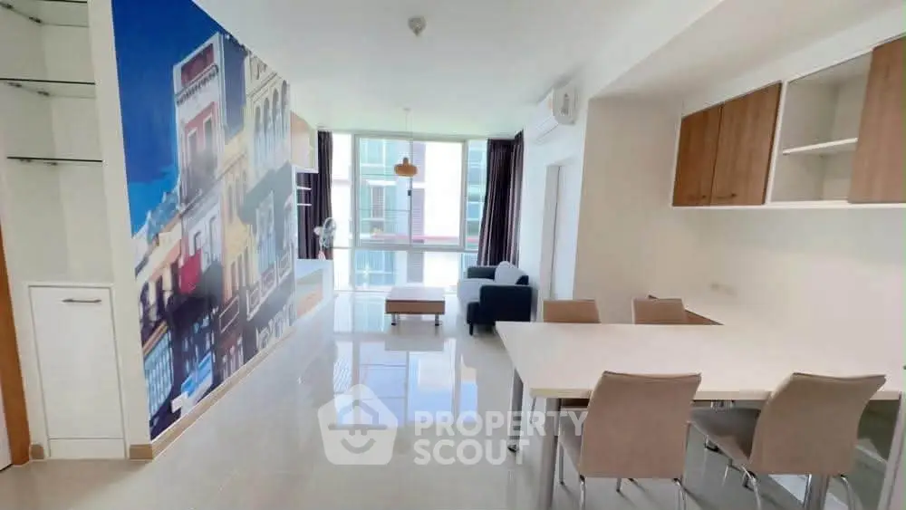 Spacious modern living room with dining area and vibrant wall art in a bright apartment.