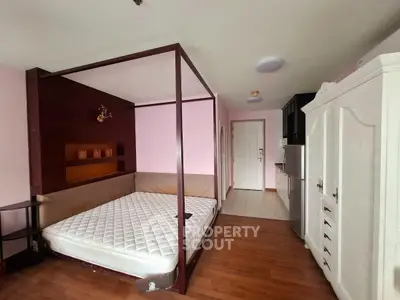 Spacious bedroom with elegant four-poster bed and ample storage in modern apartment.
