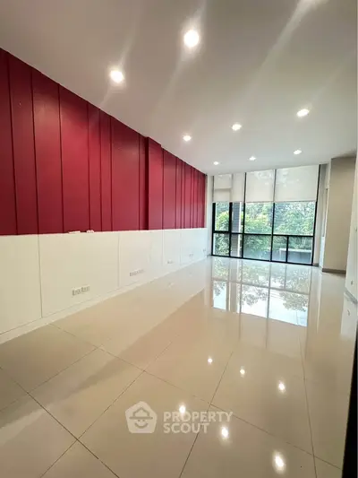 Spacious modern living room with glossy tile flooring and large windows offering natural light.