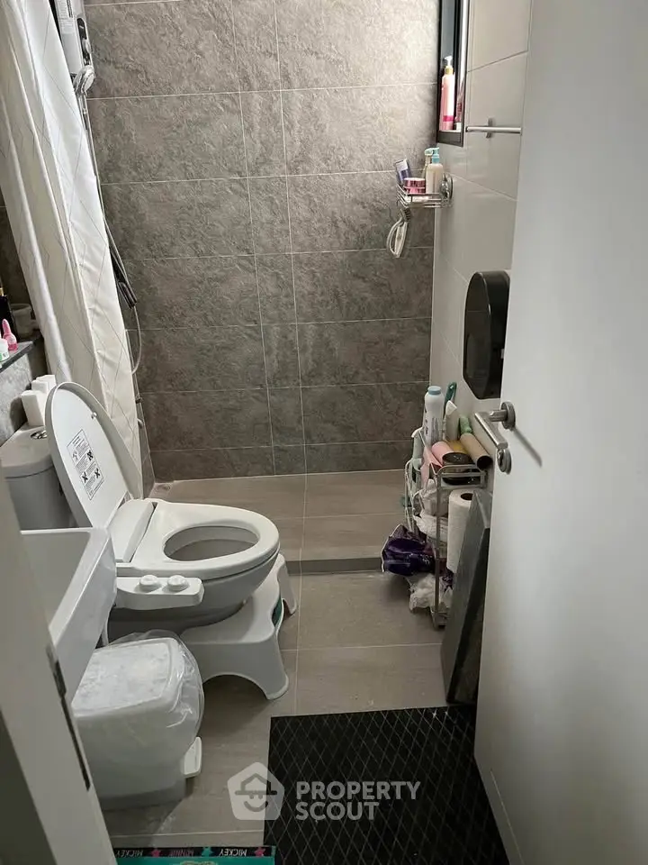 Compact bathroom with modern fixtures and tiled walls, featuring a toilet and shower area.