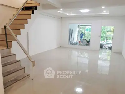 Spacious modern living room with staircase and large window overlooking garden.