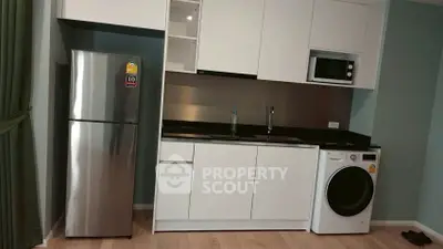 Modern kitchen with sleek appliances including fridge, microwave, and washing machine in a compact layout.