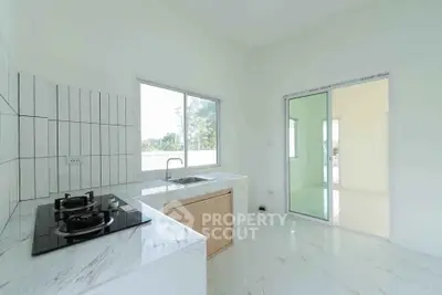 Modern kitchen with sleek gas stove and large windows in a bright, open layout.