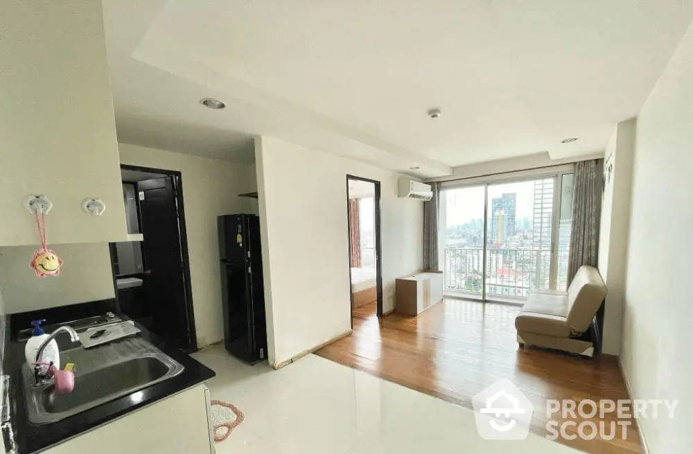 Modern apartment with open layout and city view, featuring a compact kitchen and cozy living area.