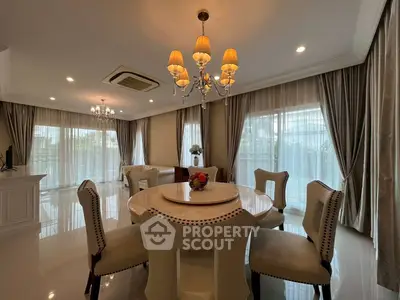 Elegant dining area with chandelier lighting and large windows in a luxurious home.