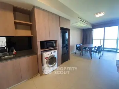 Modern kitchen and dining area with washing machine and large windows.