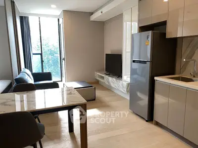 Modern open-plan living room with kitchen, featuring sleek furniture and natural light.