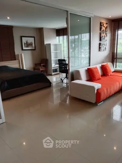 Spacious modern studio with open layout, featuring a cozy bed, stylish sofa, and large windows for natural light.